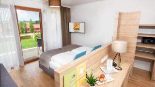 Sie sehen ein Doppelbett in einem Familienzimmer Typ Family and Friends 3 im JUFA Hotel Neutal – Landerlebnis mit Terrasse. JUFA Hotels bietet Ihnen den Ort für erlebnisreichen Natururlaub für die ganze Familie.