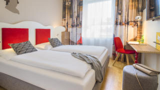 Sie sehen ein Doppelbett im Appartment4 im JUFA Hotel Salzburg City. Der Ort für erholsamen Familienurlaub und einen unvergesslichen Winter- und Wanderurlaub.