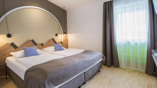 Sie sehen ein Doppelbett im Appartement 4 und 4 Plus im JUFA Hotel Wipptal. Der Ort für erholsamen Familienurlaub und einen unvergesslichen Winter- und Wanderurlaub.