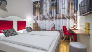 Sie sehen ein Doppelbett im Doppelzimmer im JUFA Hotel Salzburg City. Der Ort für erholsamen Familienurlaub und einen unvergesslichen Winter- und Wanderurlaub.
