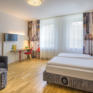 Sie sehen ein Doppelbett im FF3 Zimmer im JUFA Hotel Salzburg City. Der Ort für erholsamen Familienurlaub und einen unvergesslichen Winter- und Wanderurlaub.