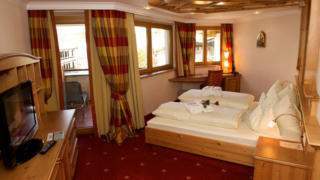 Sie sehen ein Doppelbett in Juniorsuite im JUFA Alpenhotel Saalbach. JUFA Hotels bietet erholsamen Familienurlaub und einen unvergesslichen Winterurlaub.
