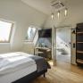 Sie sehen ein Doppelbett, Schreibtisch, Schrank und Badezimmer im Doppelzimmer Deluxe im JUFA Hotel Bregenz am Bodensee. Der Ort für einen unvergesslichen Wander-, Rad- und Kultururlaub für Familien, Freunde und Paare.