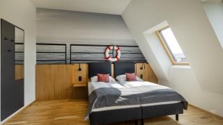 Sie sehen ein Doppelbett vor einer Fototapete in einem Doppelzimmer deluxe im JUFA Hotel Bregenz am Bodensee. Der Ort für einen unvergesslichen Wander-, Rad- und Kultururlaub für Familien, Freunde und Paare.