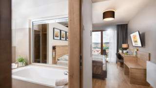 Sie sehen ein Doppelzimmer Plus im JUFA Hotel Neutal – Landerlebnis mit Badewanne. JUFA Hotels bietet Ihnen den Ort für erlebnisreichen Natururlaub für die ganze Familie.