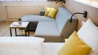 Sie sehen ein Doppelzimmer mit Sitzecke im JUFA Hotel Weiz. Der Ort für kinderfreundlichen und erlebnisreichen Urlaub für die ganze Familie.