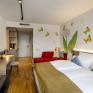 Sie sehen ein Doppelzimmer superior für bis zu 3 Personen im JUFA Hotel Bad Radkersburg mit komfortablem Boxpringbett, gemütlichem Sofa, modernem Möbliliar, kreativer Wanddeko und einer Badetasche am Zimmer