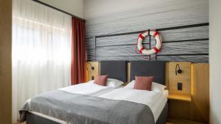 Sie sehen ein Doppelbett vor einer Fototapete in einem Doppelzimmer superior im JUFA Hotel Bregenz am Bodensee. Der Ort für einen unvergesslichen Wander-, Rad- und Kultururlaub für Familien, Freunde und Paare.
