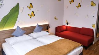 Sie sehen ein Doppelzimmer superior im neuen JUFA Hotel Bad Radkersburg mit komfortablen Boxspringbett und Schlafcouch.