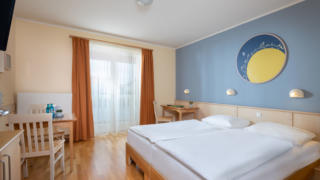 Sie sehen ein Doppelzimmer mit Doppelbett - den Galaxien gewidmet im JUFA Hotel Nördlingen. Der Ort für kinderfreundlichen und erlebnisreichen Urlaub für die ganze Familie.