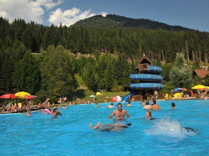Menschen baden im Erlebnisschwimmbad in Gitschtal im Sommer in der Nähe von JUFA Hotels. Der Ort für erholsamen Familienurlaub und einen unvergesslichen Winter- und Wanderurlaub.
