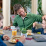 Sie sehen einen Vater mit zwei Kinder beim Essen von Kuchen im JUFA Kempten. Der Ort für kinderfreundlichen und erlebnisreichen Urlaub für die ganze Familie.