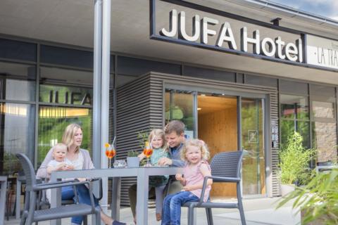 Sie sehen eine Familie vor dem Hoteleingang im JUFA Hotel Wipptal. Der Ort für erholsamen Familienurlaub und einen unvergesslichen Winter- und Wanderurlaub.