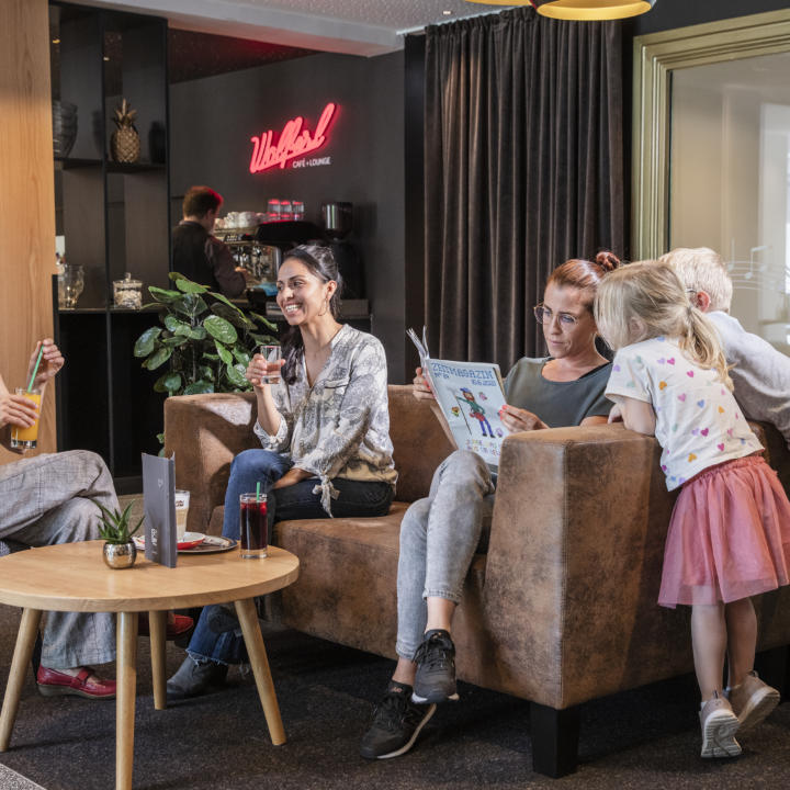 Sie sehen eine Familie mit Kindern in der Lounge im JUFA Hotel Salzburg City. Der Ort für erholsamen Familienurlaub und einen unvergesslichen Winter- und Wanderurlaub.