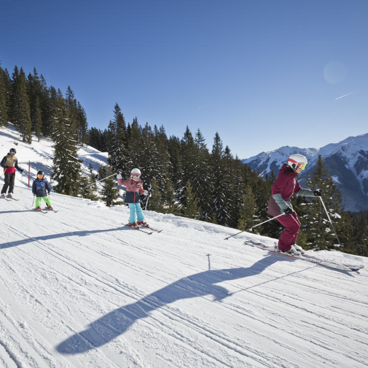 Sie sehen eine Familie bei einer Skiabfahrt im Skicircus Saalbach Hinterklemm. JUFA Hotels bietet erholsamen Familienurlaub und einen unvergesslichen Winterurlaub.