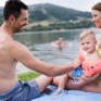 Sie sehen eine Familie am Stubenbergsee im Sommer. JUFA Hotels bietet tollen Sommerurlaub an schönen Seen für die ganze Familie.