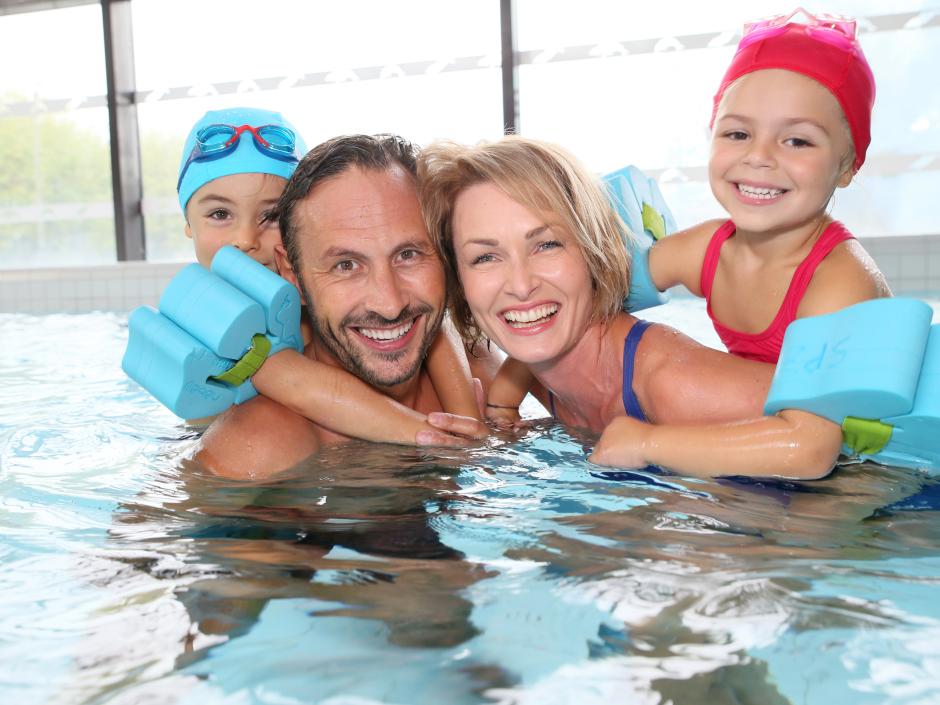 Sie sehen eine Familie mit Kindern beim Schwimmen in einem Hallenbad in der Nähe von JUFA Hotels
