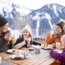 Sie sehen eine Familie beim Nachmittagskuchen auf der Terrasse des JUFA Hotel Laterns - Klangholzhus. Der ideale Ort für einen abwechslungsreichen Familien-Winterurlaub und unvergessliche Tage im Schnee.
