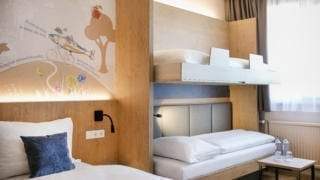 Sie sehen ein Familienzimmer FF4 mit Etagenklappbetten im JUFA Hotel Weiz. Der Ort für kinderfreundlichen und erlebnisreichen Urlaub für die ganze Familie.