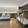 Sie sehen ein Vierbettzimmer mit Doppelbett und Stockbett im JUFA Hotel Hamburg HafenCity. Der Ort für erlebnisreichen Städtetrip für die ganze Familie und der ideale Platz für Ihr Seminar.