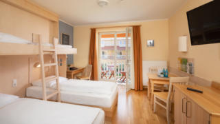 Sie sehen vier Einzelbetten mit Treppe im Familienzimmer im JUFA Hotel Nördlingen. Der Ort für kinderfreundlichen und erlebnisreichen Urlaub für die ganze Familie.