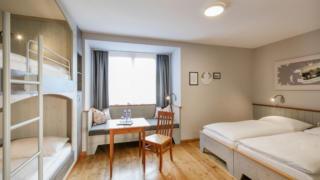 Sie sehen ein Mehrbettzimmer im JUFA Hotel Eisenerz. Der Ort für erholsamen Familienurlaub und einen unvergesslichen Winter- und Wanderurlaub.