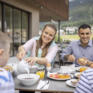 Sie sehen eine Familie beim Frühstücken auf der Terrasse des JUFA Hotel Savognin***s.