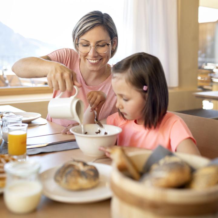 Sie sehen eine Mutter und ihre Tochter beim Frühstücken im JUFA Hotel Laterns-Klangholzhus in Vorarlberg.