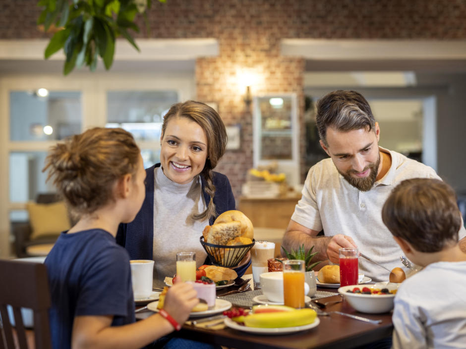 Sie sehen eine Familie am Frühstückstisch mit Mama, Papa, Tochter und Sohn. JUFA Hotels bietet erholsamen Familienurlaub und einen unvergesslichen Winter- und Wanderurlaub.