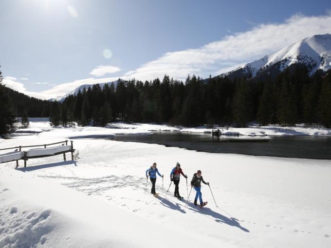 Sie sehen Schneeschuhwanderer an einem zugefrorenen See im Murtal im Winter. JUFA Hotels bietet erholsamen Familienurlaub und einen unvergesslichen Winterurlaub.