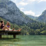 Sie sehen zwei Frauen beim Sonnebaden am Steg - unweit vom JUFA Hotel Pyhrn-Priel. Der Ort für tollen Sommerurlaub an schönen Seen für die ganze Familie.