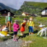 Sie sehen ein Mädchen, das vor bunten Heidi Figuren auf der Alm steht. JUFA Hotels bietet erholsamen Ski- und Wanderurlaub für Familien in Kärnten.