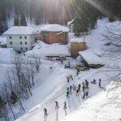 Sie sehen eine Außenansicht vom JUFA Hotel Altaussee*** mit einer Skigruppe im Winter. JUFA Hotels bietet erholsamen Familienurlaub und einen unvergesslichen Winterurlaub.
