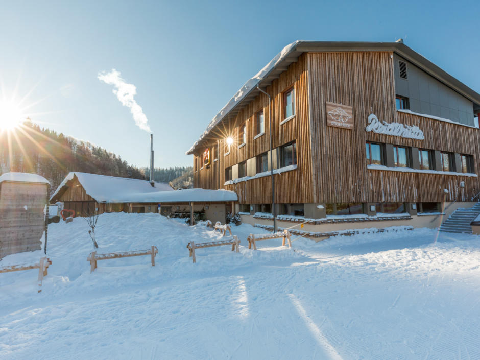 Aussenansicht vom JUFA Hotel Annaberg - Bergerlebnis-Resort mit Schriftzug im Winter. Der Ort für erholsamen Familienurlaub und einen unvergesslichen Winter- und Wanderurlaub.