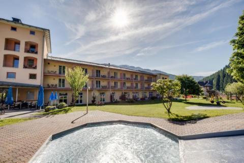 Sie sehen eine Außenansicht vom JUFA Hotel Veitsch mit Kinderbecken im Sommer. JUFA Hotels bietet kinderfreundlichen und erlebnisreichen Urlaub für die ganze Familie.