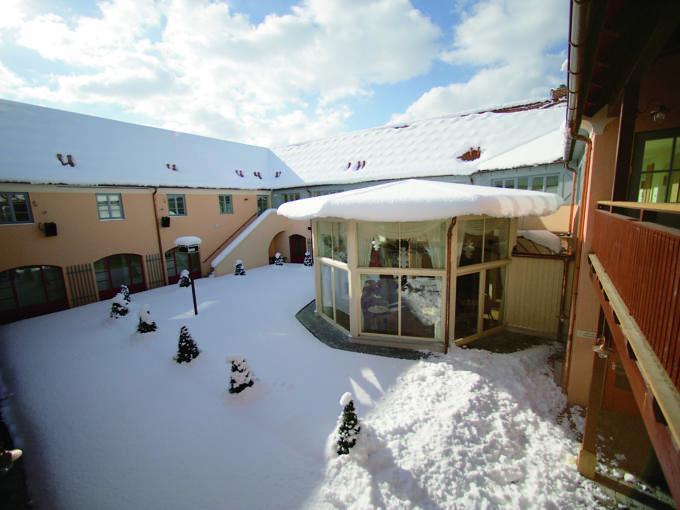 Sie sehen den Innenhof mit Pavillion iim Winter vom JUFA Hotel Pöllau-Bio-Landerlebnis. Der Ort für erlebnisreichen Natururlaub für die ganze Familie.