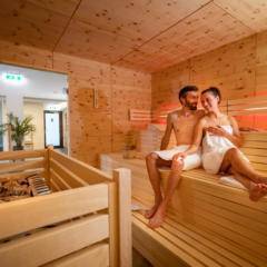 Sie sehen ein Paar, das sich im Saunabereich des JUFA Alpenhotel Saalbach**** entspannt. JUFA Hotels bietet erholsamen Familienurlaub und einen unvergesslichen Winter- und Wanderurlaub.
