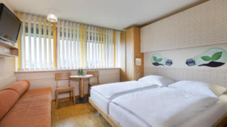 Sie sehen ein Doppelzimmer im JUFA Hotel Bleiburg / Pliberk. Der Ort für erholsamen Familienurlaub und einen unvergesslichen Winter- und Wanderurlaub.