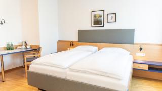 Sie sehen ein Bild vom Doppelzimmer mit Doppelbett, Tisch und Wasserkocher im JUFA Hotel Garni Stubenberg.