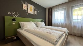 Sie sehen ein Doppelbett im Appartement für 2 Personen im JUFA Hotel Graz Süd. Der Ort für erlebnisreichen Städtetrip für die ganze Familie und der ideale Platz für Ihr Seminar.