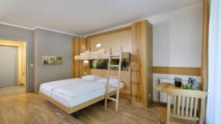 Sie sehen ein Zimmer aus der Kategorie FF3 im JUFA Hotel im Weitental / Bruck a.d. Mur. JUFA Hotels bietet erholsamen Familienurlaub und einen unvergesslichen Winter- und Wanderurlaub.