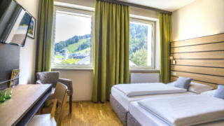 Sie sehen ein Doppelzimmer Superior im JUFA Hotel Schladming. Der Ort für erholsamen Ski- und Wanderurlaub für Familien.