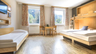 Sie sehen ein Zimmer aus der Kategorie FF4 im JUFA Hotel Schladming. Der Ort für erholsamen Ski- und Wanderurlaub für Familien.