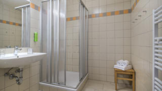 Sie sehen ein Badezimmer aus der Kategorie FF4 im JUFA Hotel Schladming. Der Ort für erholsamen Ski- und Wanderurlaub für Familien.