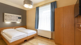 Sie sehen ein Doppelbett. So sind die Doppelzimmer und Einzelzimmer im JUFA Klosterhotel Judenburg ausgestattet. Der Ort für erholsamen Familienurlaub und einen unvergesslichen Winter- und Wanderurlaub.