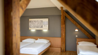 Sie sehen ein Doppelbett und ein Einzelbett. So sind die Family Friends 3 Zimmer im JUFA Klosterhotel Judenburg ausgestattet. Der Ort für erholsamen Familienurlaub und einen unvergesslichen Winter- und Wanderurlaub.