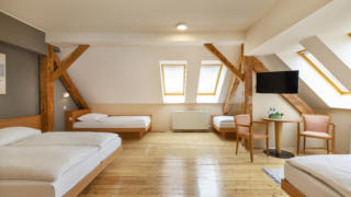 Sie sehen ein Doppelbett und drei Einzelbetten. So sind die Family Friends 5 Zimmer und Family Friends 4 Zimmer im JUFA Klosterhotel Judenburg ausgestattet. Der Ort für erholsamen Familienurlaub und einen unvergesslichen Winter- und Wanderurlaub.