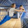 Sie sehen zwei Kinder auf einer Brücke zwischen zwei Türmen im Indoor-KInderspielbereich im JUFA Hotel Bad Radkersburg.