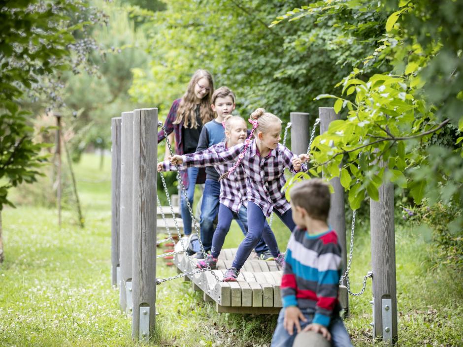 Sie sehen Kinder auf dem Parcour am Spielplatz im JUFA Hotel Tieschen – Bio-Landerlebnis. Der Ort für kinderfreundlichen und erlebnisreichen Urlaub für die ganze Familie.