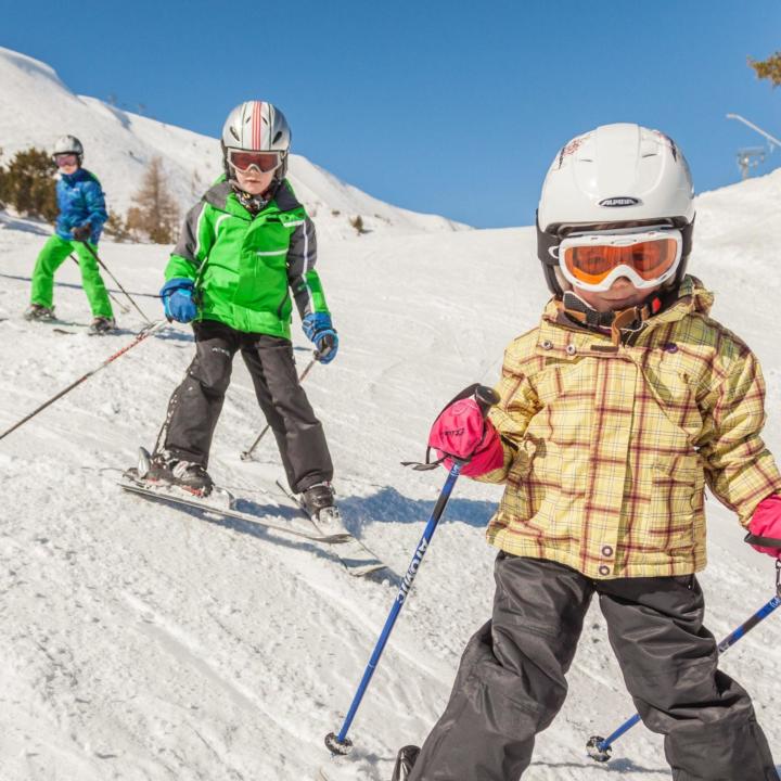 Kinder beim Skifahren im Skigebiet Turracher Höhe in Kärnten. JUFA Hotels bietet erholsamen Familienurlaub und einen unvergesslichen Winterurlaub.